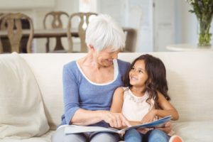 Grandmother and granddaughter interacting while looking at photo album in living room